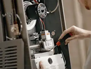 Furnace repair technician inspecting internal components and wiring in Raleigh, NC