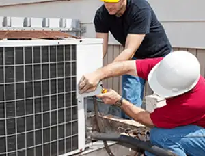 HVAC technicians repairing an outdoor AC unit on a rooftop in Raleigh, NC
