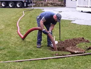 Septic pumping technician servicing a residential septic tank with a vacuum hose in Raleigh, NC