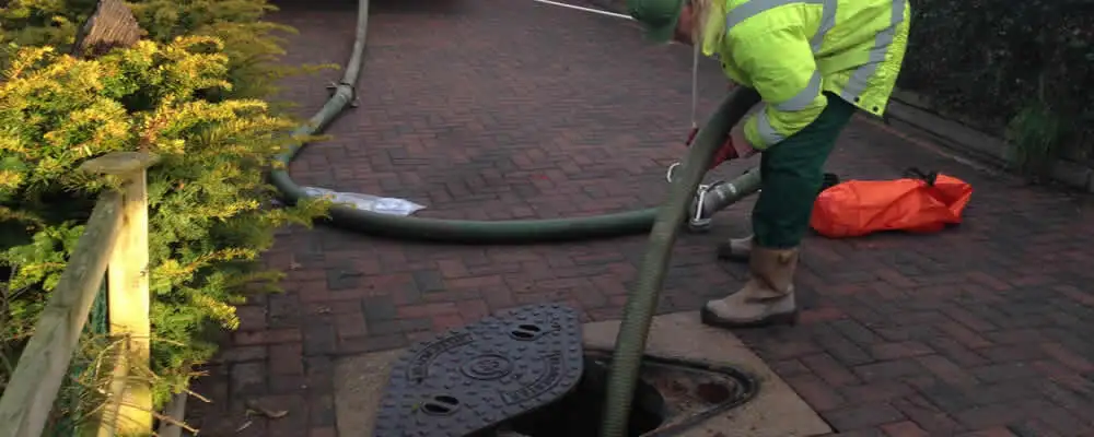 Septic tank cleaning technician servicing a septic tank with a vacuum hose in Raleigh, NC