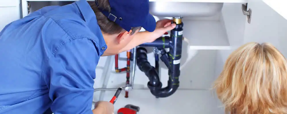 Plumber repairing under-sink drain pipes and fittings in Raleigh, NC